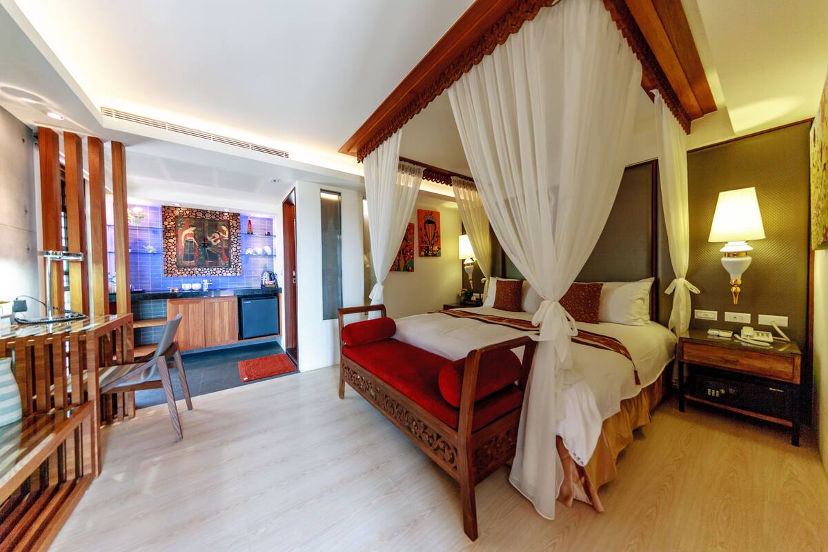 Un dormitorio con una cama con dosel, un escritorio de madera y una silla.