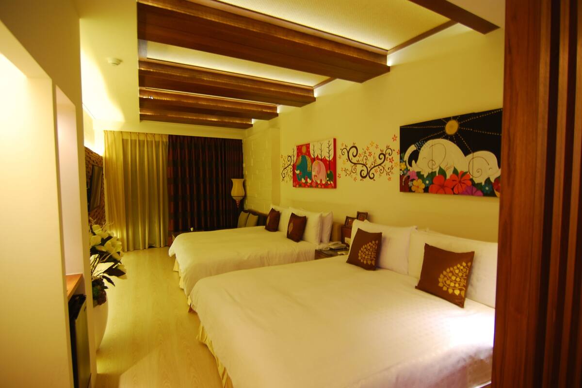 Habitación de hotel con dos camas, techo de madera y obras de arte en las paredes.