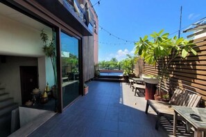 Um pátio moderno ao ar livre, com cerca de madeira, plantas em vasos e mobiliário exterior.