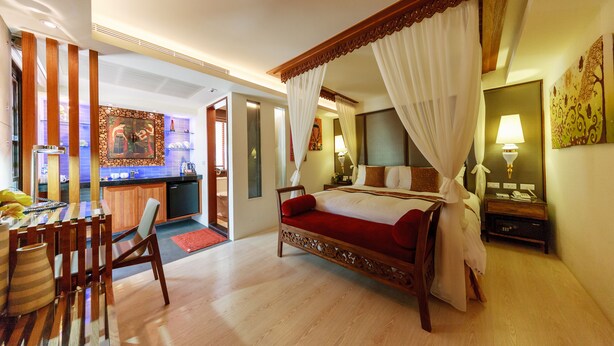 A spacious bedroom with a large bed, a sitting area with a table and chairs, and a view of the kitchen and living area. - A&L Inn (Hengchun)