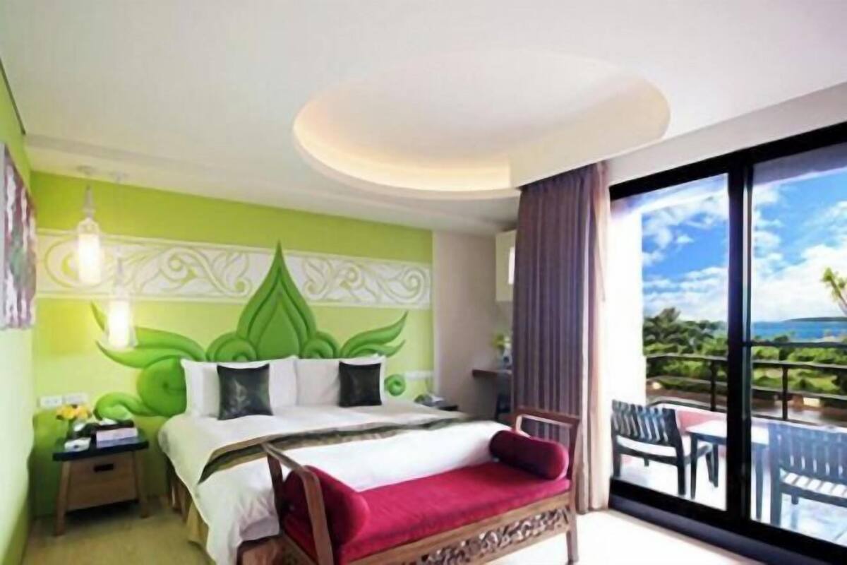Una habitación de hotel con cama, mesita de noche, silla y balcón con vistas.