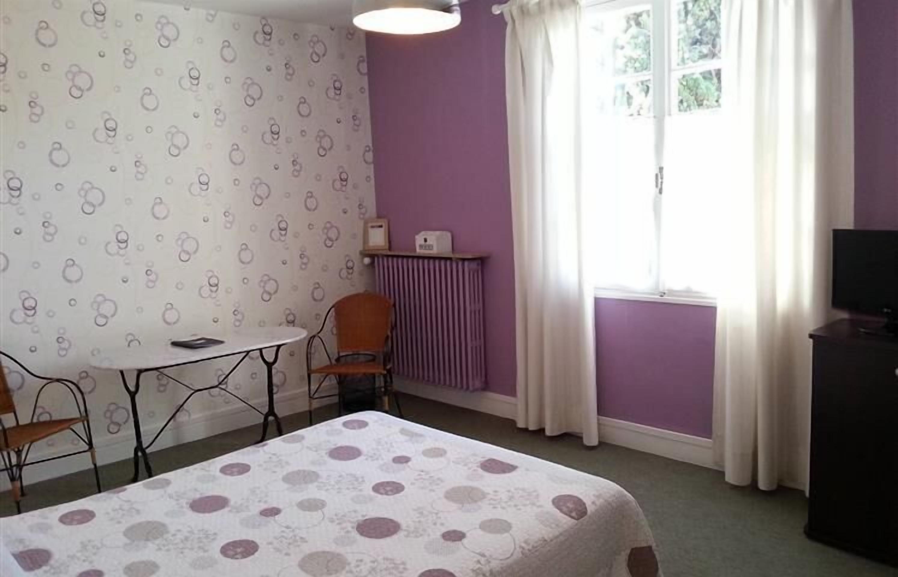 A room with a bed, a table, a chair, a radiator, and a TV.