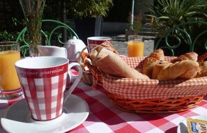 A table with a checkered tablecloth, a basket of bread, a teapot, and a cup labeled "Dejeuner gourmand". - Hôtel La Résidence (Villeneuve-sur-Lot)