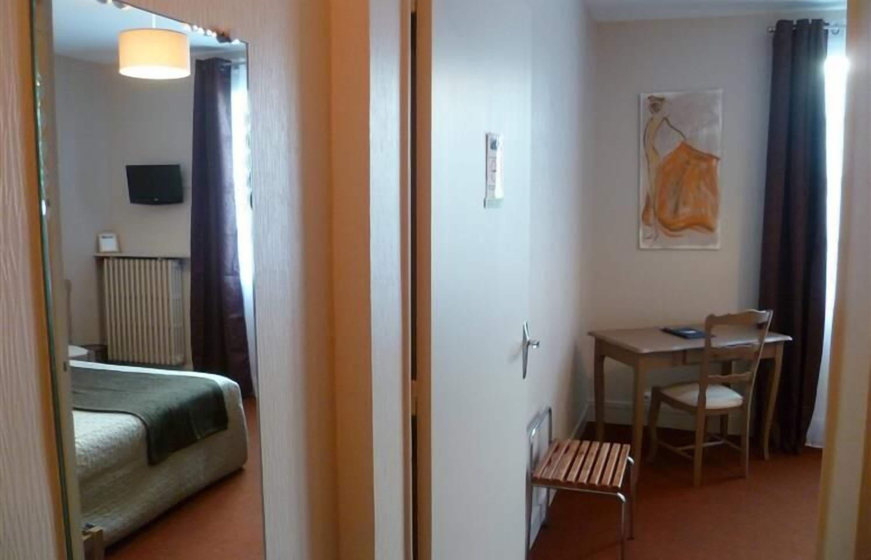 Et hotelværelse med seng, skrivebord, stol og radiator.