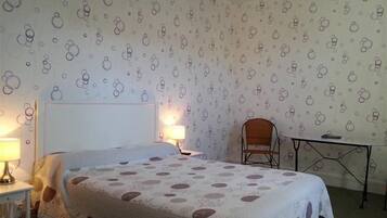 A bedroom with a bed, two bedside lamps, a chair, and a small table.