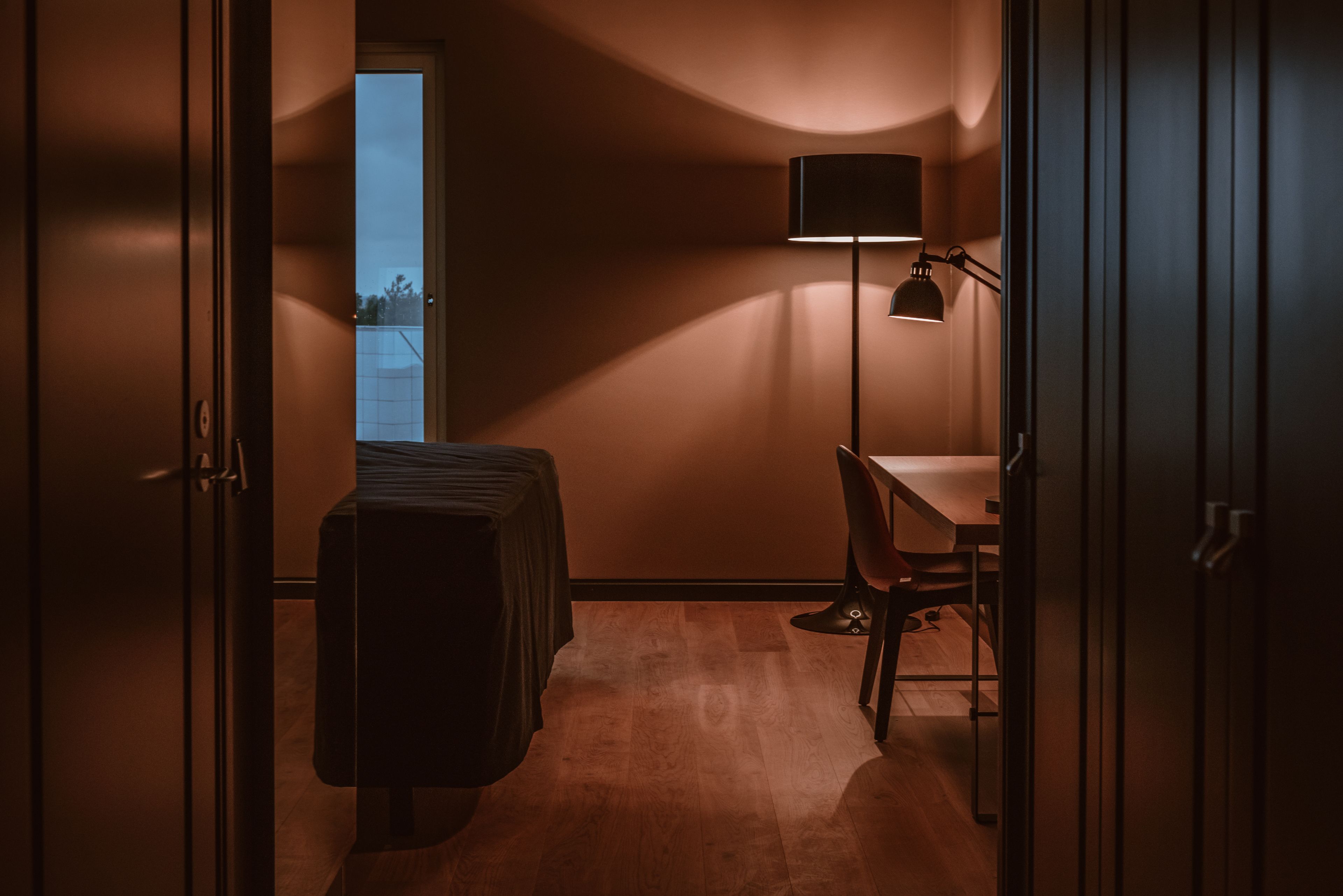 Um quarto com uma cama, uma escrivaninha e um abajur.
