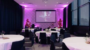 Una sala de conferencias con varias mesas redondas, sillas y una pantalla grande que muestra 'CLARION MEETING'.