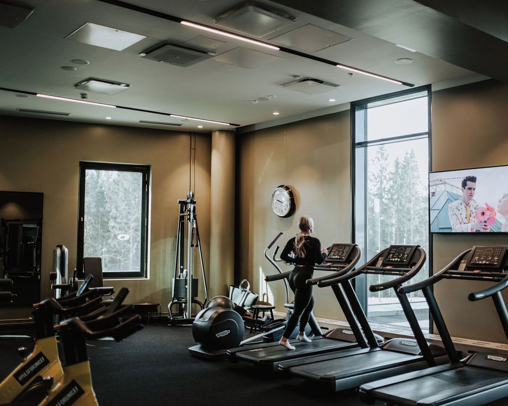 A gym with treadmills, weight machines, and a large window.