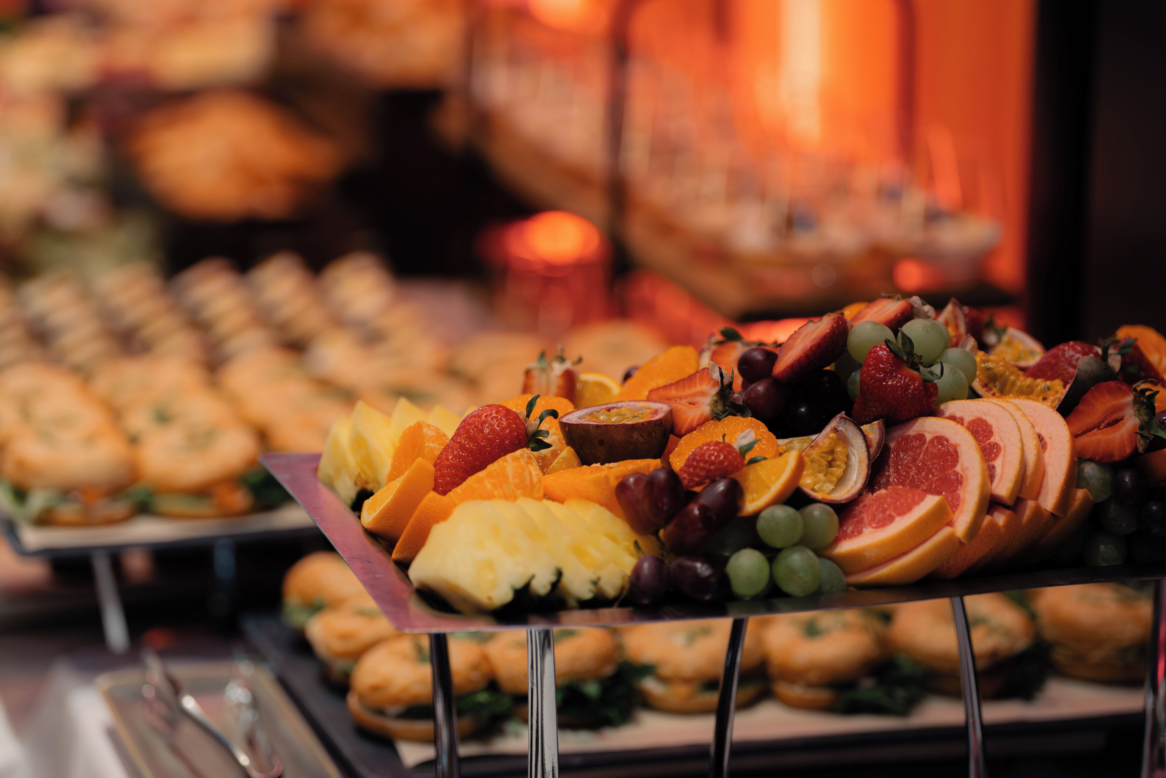 A buffet with a variety of food items including fruits, pastries, and sandwiches.