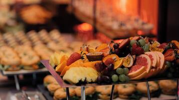 A buffet with a variety of food items including fruits, pastries, and sandwiches.