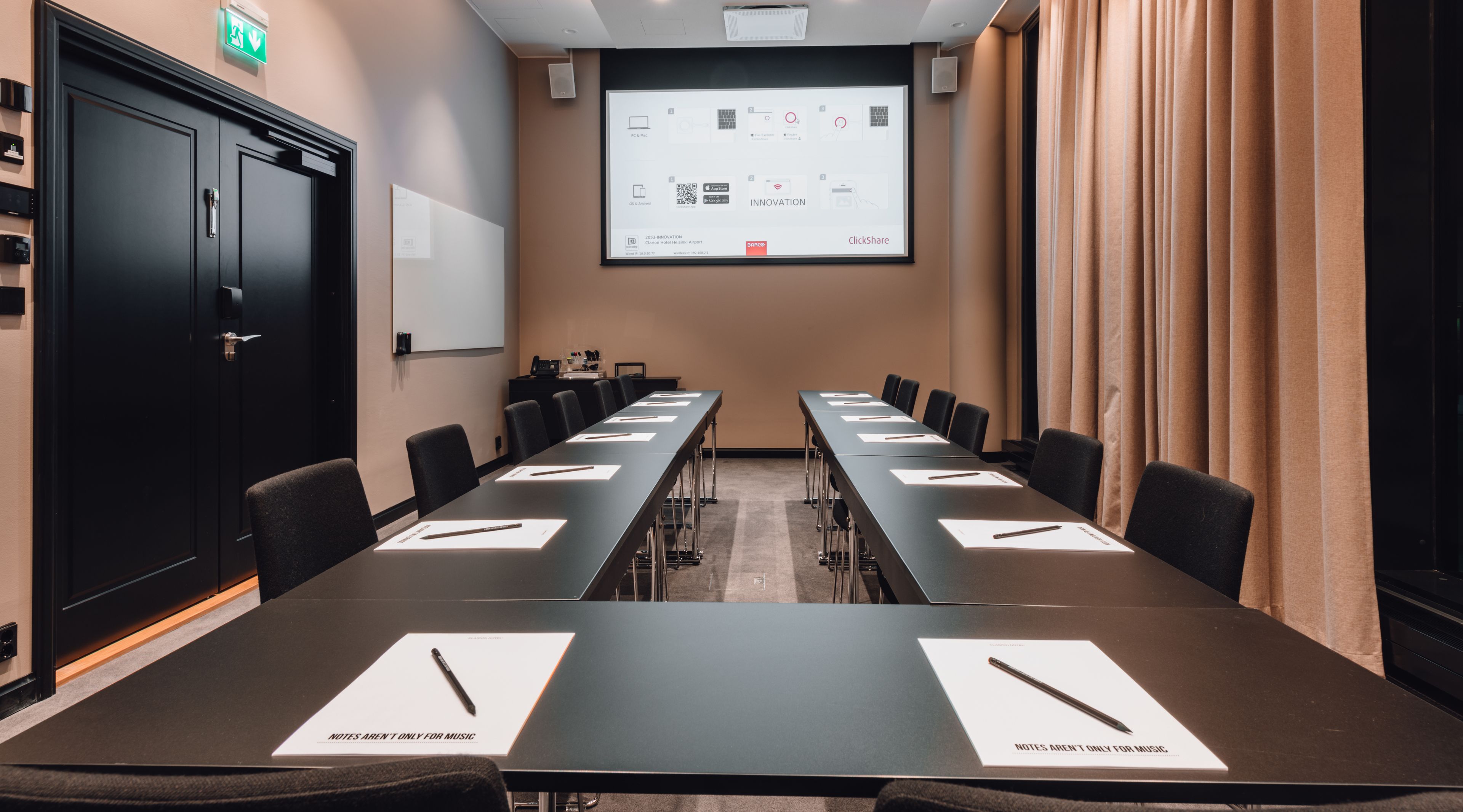 A conference room with a long table, chairs, a projector screen, and a whiteboard.