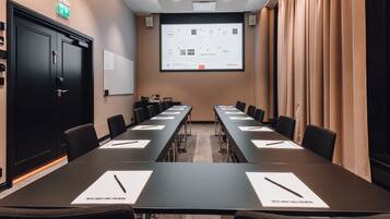 A conference room with a long table, chairs, a projector screen, and a whiteboard.