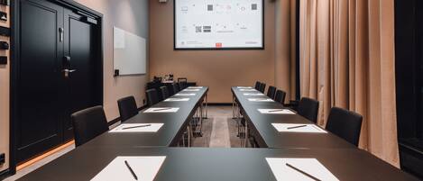 A conference room with a long table, chairs, a projector screen, and a whiteboard.
