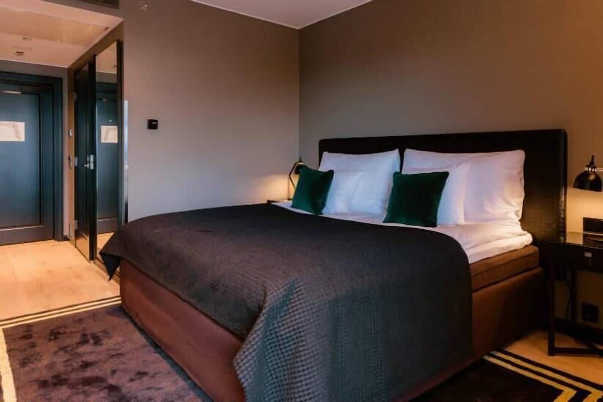 Ein Hotelzimmer mit einem großen Bett, einem Nachttisch und einem Schreibtisch mit Lampe.