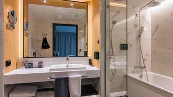 Un baño moderno con un espejo grande, lavamanos blanco y cabina de ducha con paredes de vidrio.