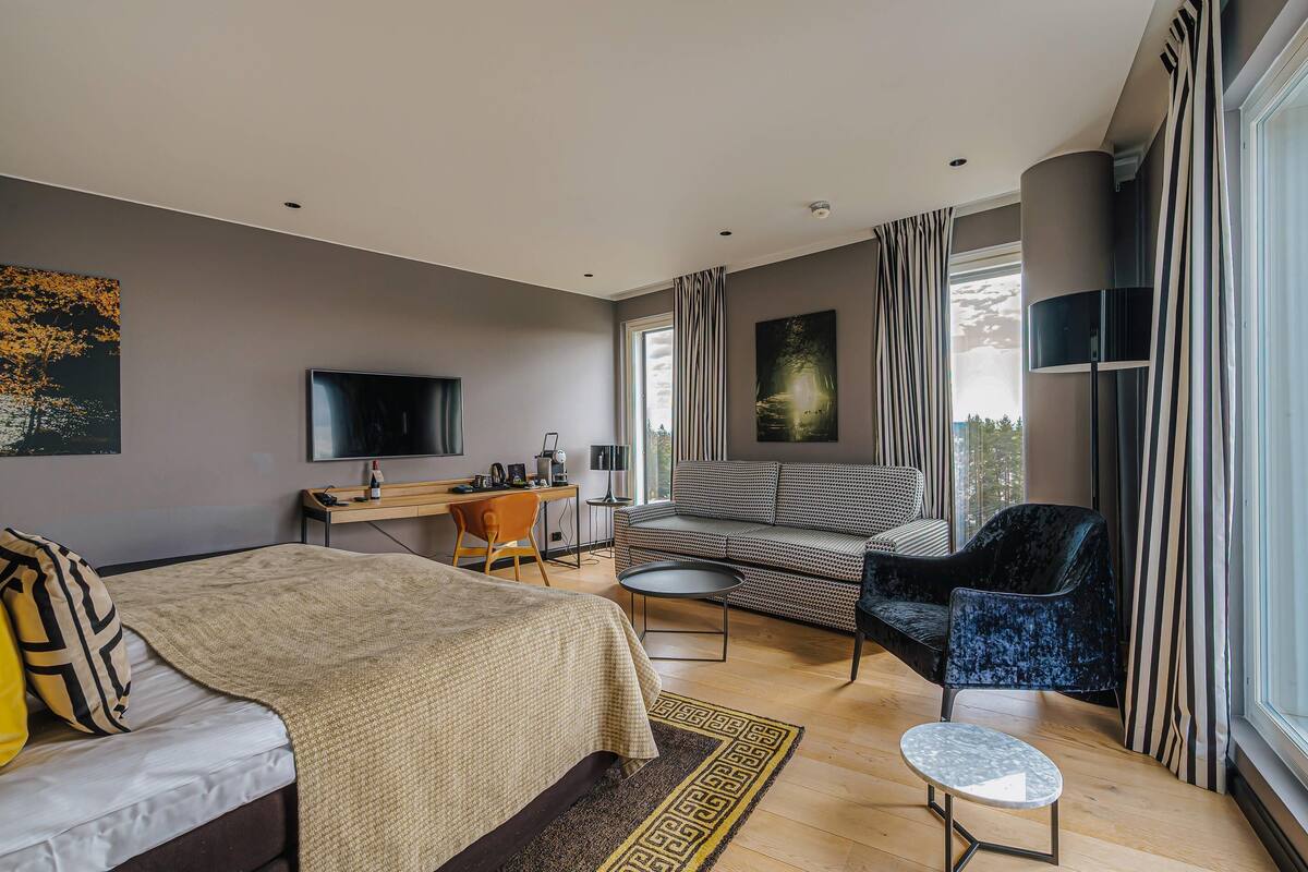 Ein modernes Hotelzimmer mit einem Bett, einem Schreibtisch, einem Sofa und einem Sessel.