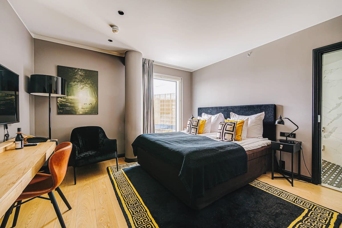 Ein modernes Hotelzimmer mit einem großen Bett, einem Schreibtisch, einem Stuhl und einem Fernseher.