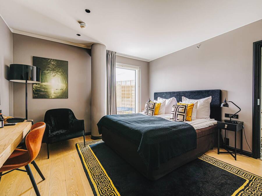 Ein modernes Hotelzimmer mit einem großen Bett, einem Schreibtisch, einem Stuhl und einem Fernseher.