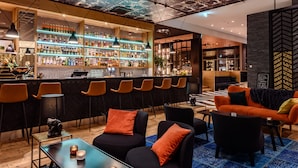 Zona de bar con diversas opciones de asientos y una variedad de botellas de licor en estanterías.