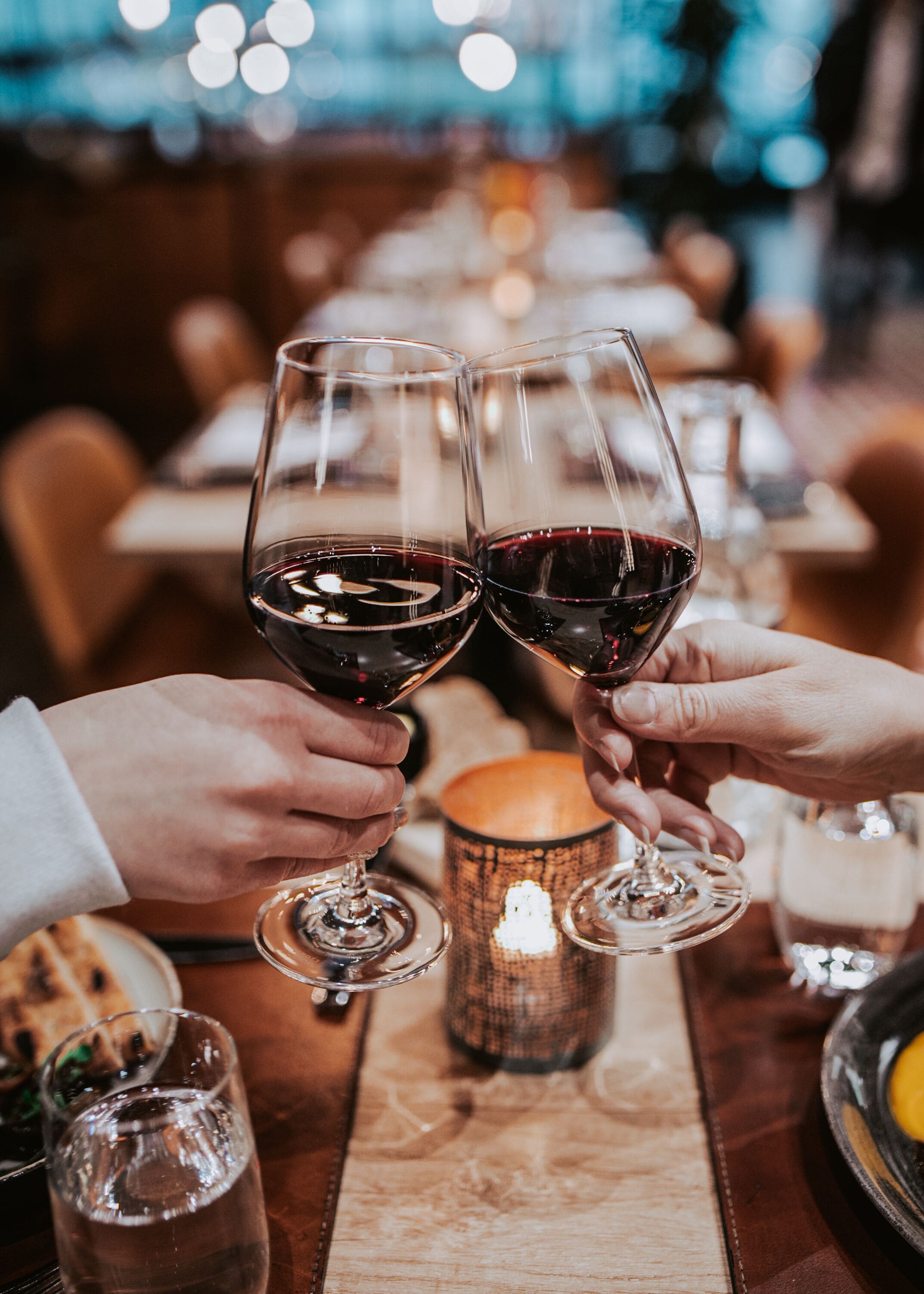 Two people toasting with wine glasses in a restaurant setting.