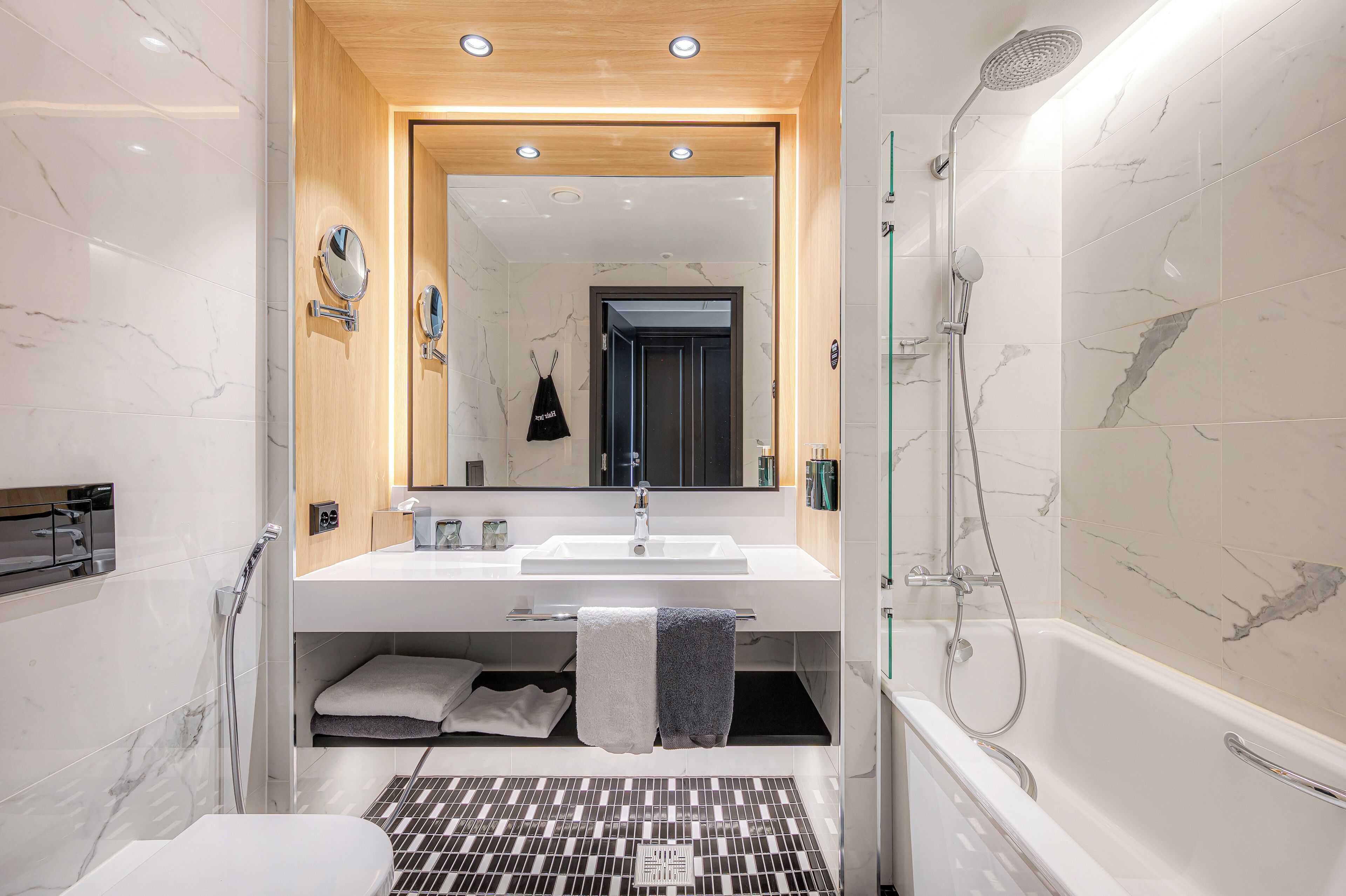 Une salle de bain moderne avec un grand miroir, un lavabo et une douche.