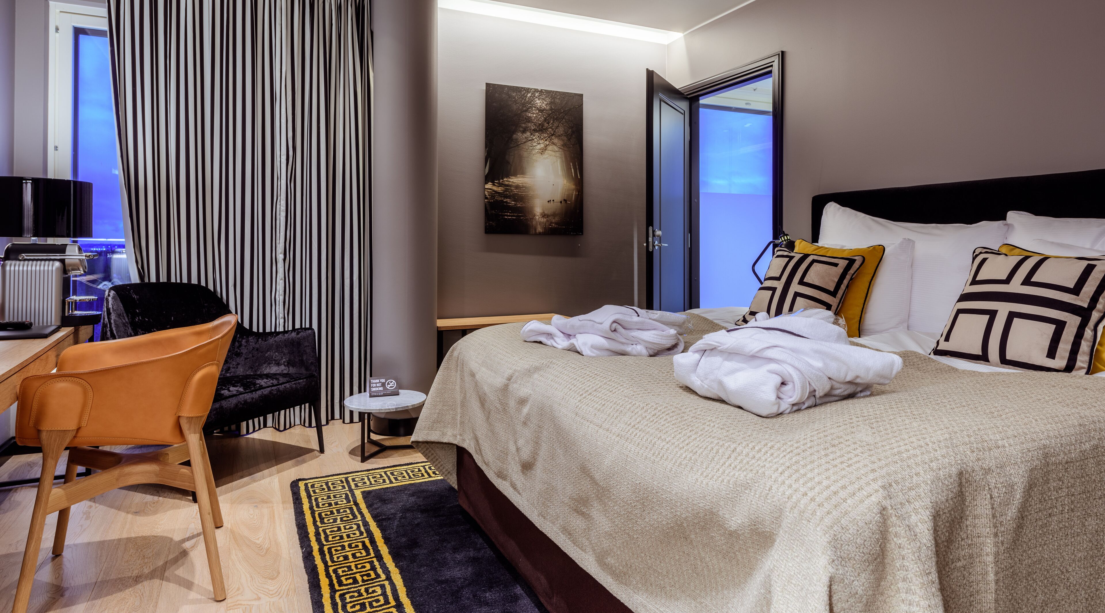 A hotel room with a bed, a desk, a chair, and a view of the outside.
