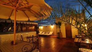 Terraza con vista al atardecer, asientos al aire libre y una palmera.