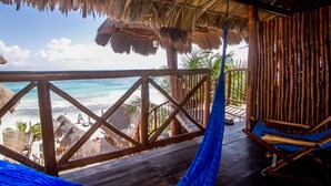 A wooden deck with a thatched roof overlooking a beach. - Playa Canek Beachfront Eco Hotel (Tulum)