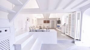 Un interior moderno y blanco con una escalera que lleva a una sala de estar, un comedor y una cocina.