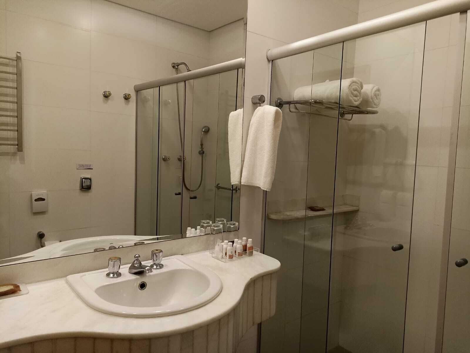A modern bathroom with a large mirror, a sink, a glass-enclosed shower, and neatly arranged towels.