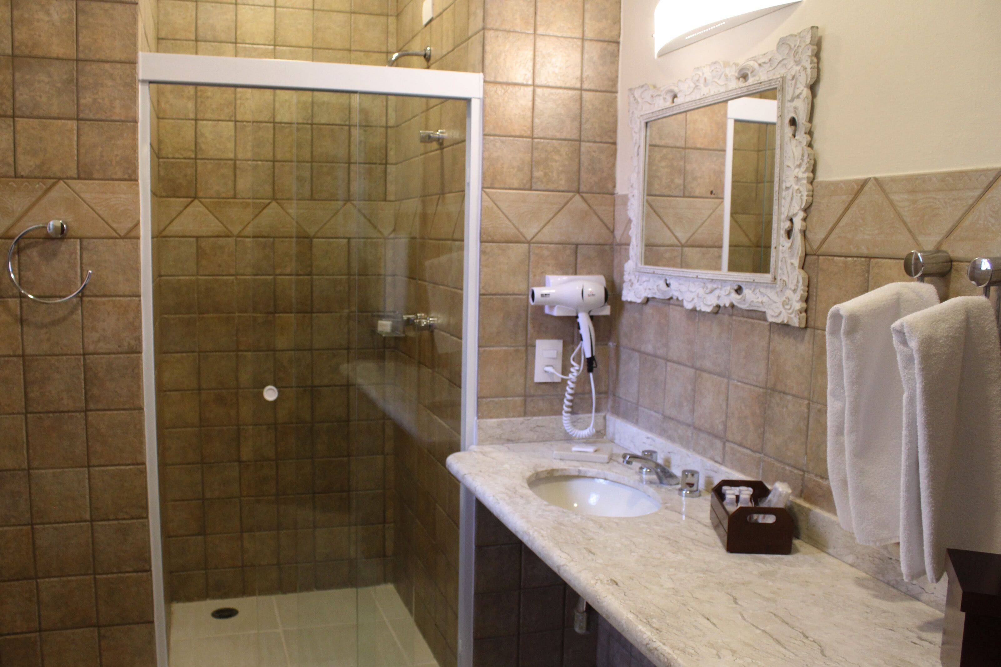 Un baño con cabina de ducha de vidrio, un lavabo, un espejo y toallas.