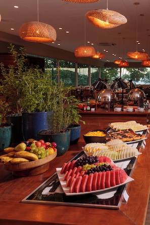 A buffet with various fruits and vegetables, potted plants, and a coffee station. - Hotel Villa Rossa (Sao Roque)