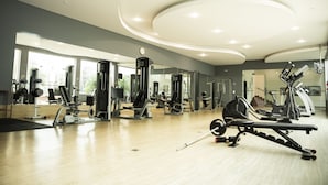 Un gimnasio con diversos equipos de ejercicio, amplias ventanas y un diseño de techo moderno.
