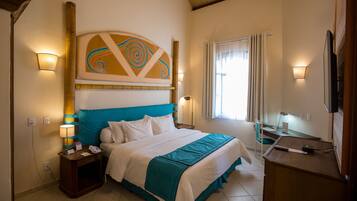 A hotel room with a bed, bedside lamps, a desk, and a television.