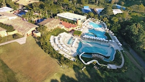 An aerial view of a resort with multiple swimming pools, sun loungers, and a large building likely serving as a hotel or clubhouse. - Hotel Villa Rossa (Sao Roque)