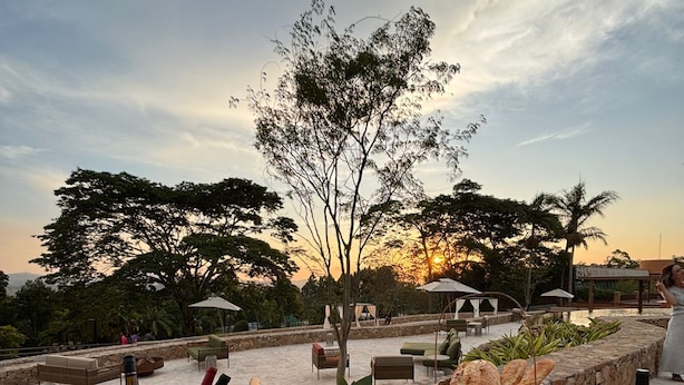Un área de comedor al aire libre con una mesa dispuesta para una comida, con una variedad de frutas y botellas de vino.