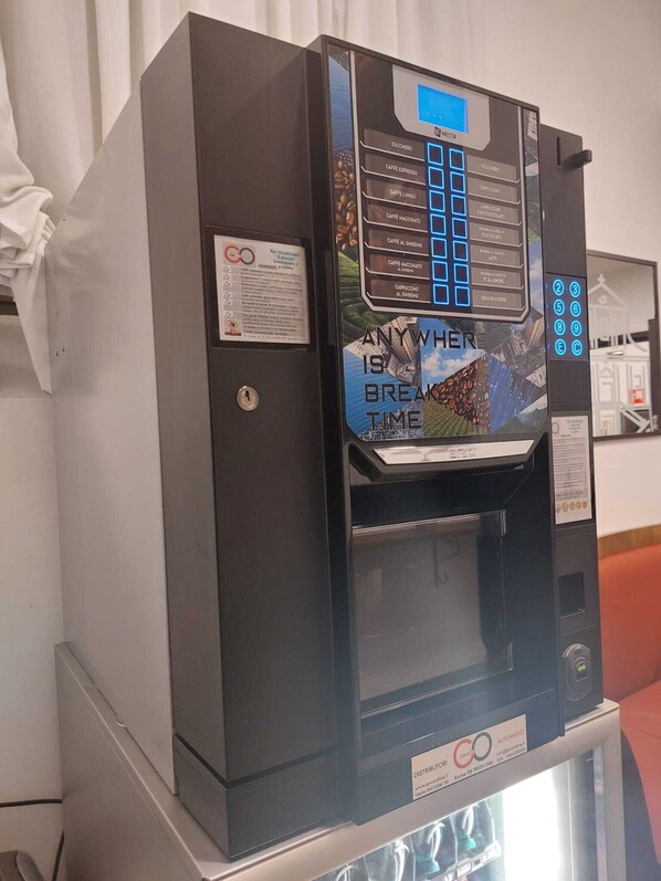 Máquina de venda automática de café com visor digital e diversas opções.