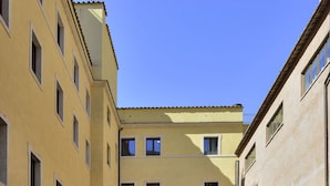 A courtyard with a central pathway, surrounded by buildings with multiple windows and balconies. - Casa I Cappuccini (Rome)