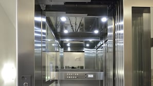 An elevator with a metallic interior, control panel, and emergency exit sign. - Casa I Cappuccini (Rome)