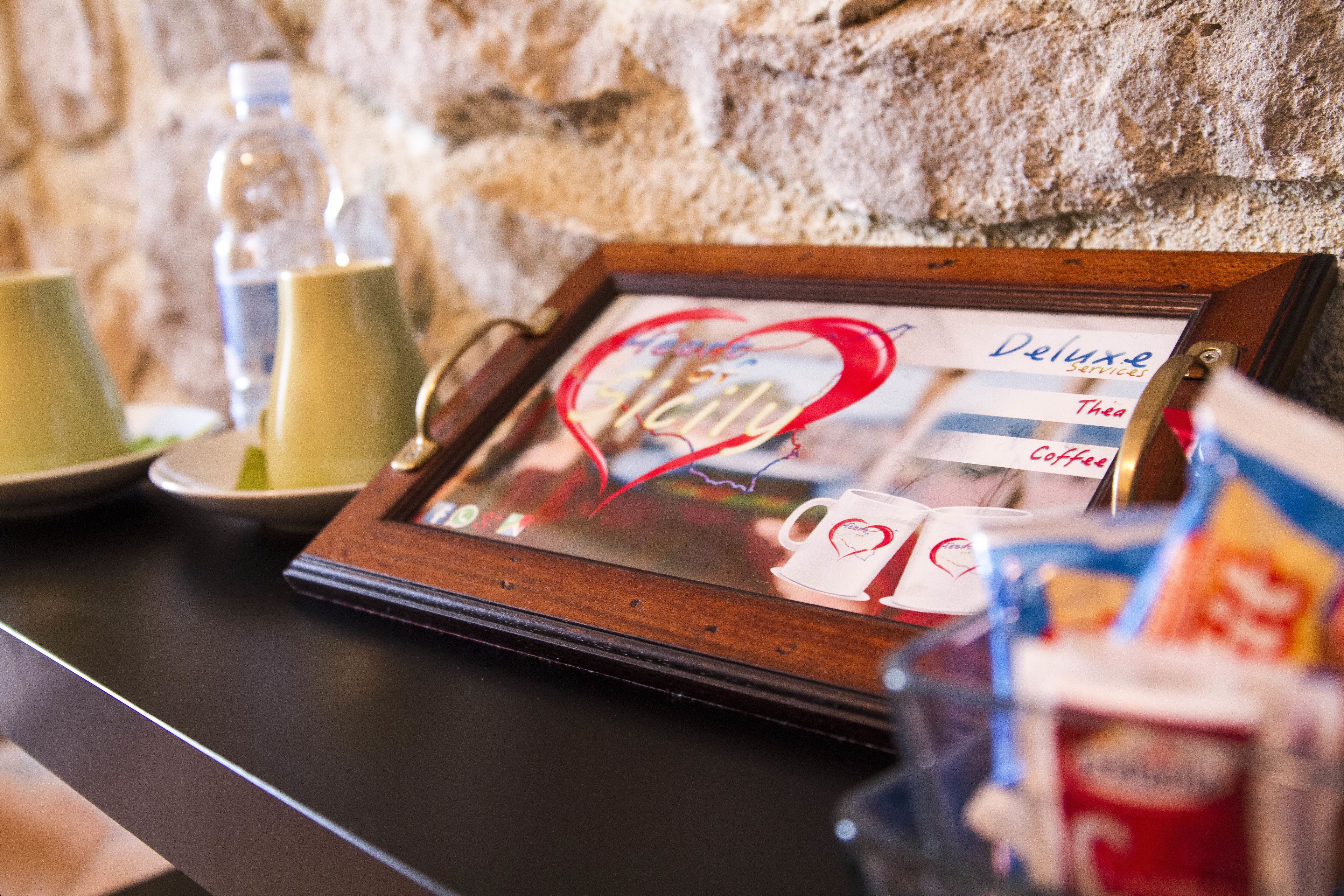 A framed picture with a heart design and text, placed on a table with a stone wall background.