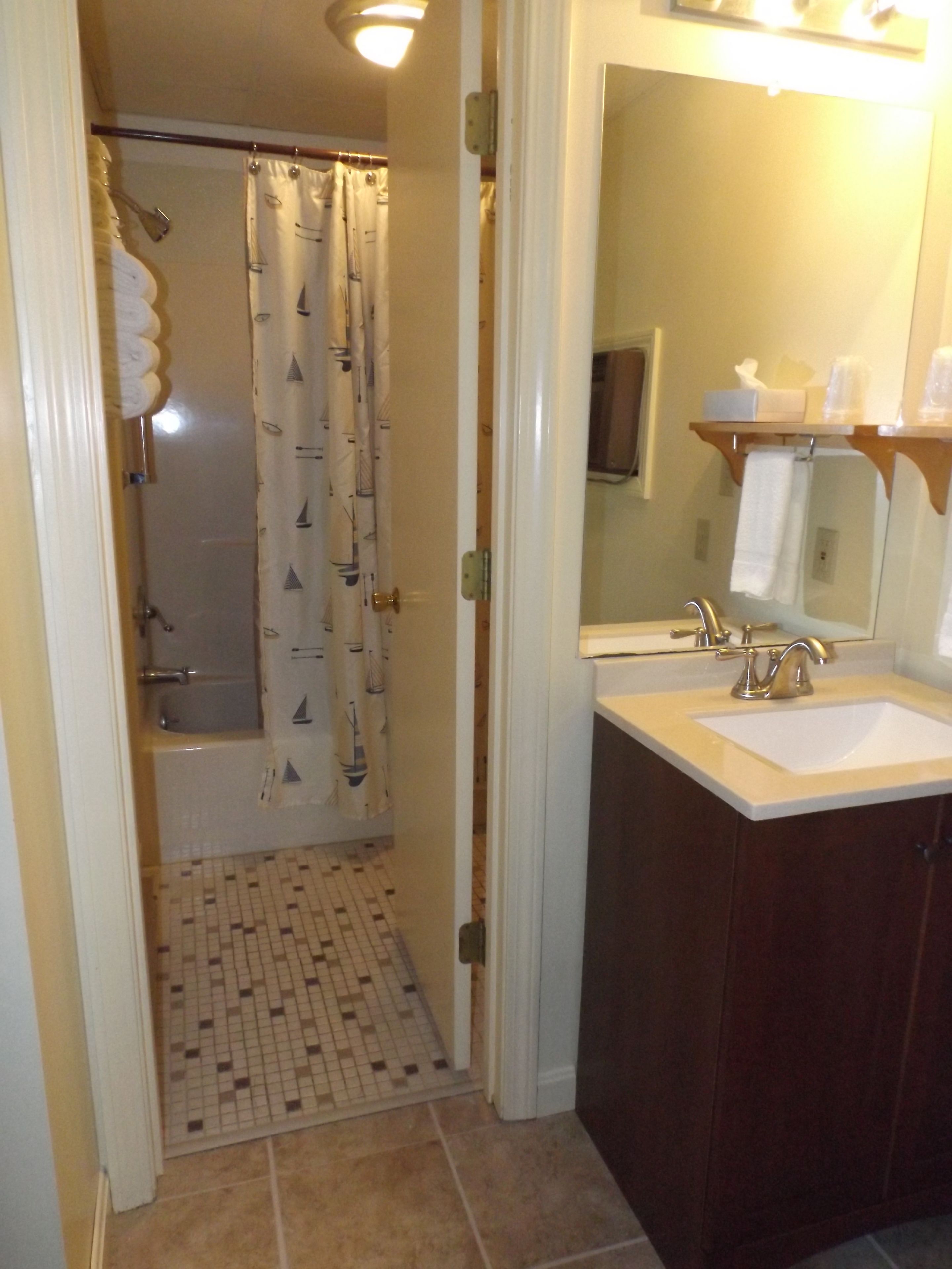 Un baño con ducha, lavamanos y espejo.