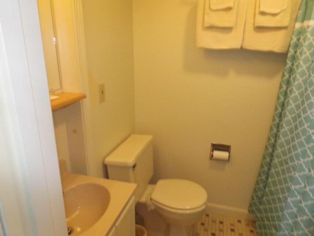 Un baño pequeño con inodoro, lavamanos y toallero.
