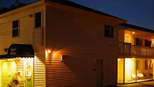 Un hotel con reception, un balcone con posti a sedere all'aperto e un ingresso ben illuminato.