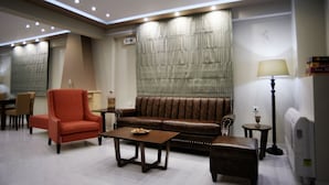 Een moderne zithoek met een bruine leren bank, een rode fauteuil en een houten salontafel.