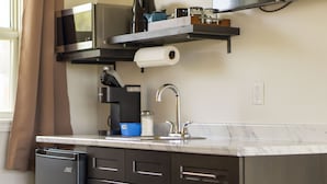 A modern kitchen with a built-in dishwasher, a stainless steel microwave, a coffee maker, and a roll of paper towels on a shelf. - Wayside Motel Manitoulin (Assiginack)