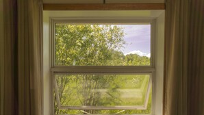 A window with a view of a green landscape and trees. - Wayside Motel Manitoulin (Assiginack)