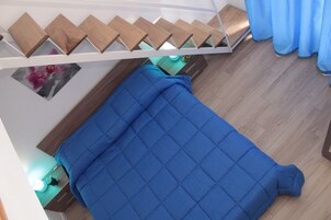 Un dormitorio con cama, escalera de madera y cortina azul.