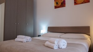 A hotel room with a large bed, two paintings on the wall, and a wardrobe. - B&B Teatro (Palermo)