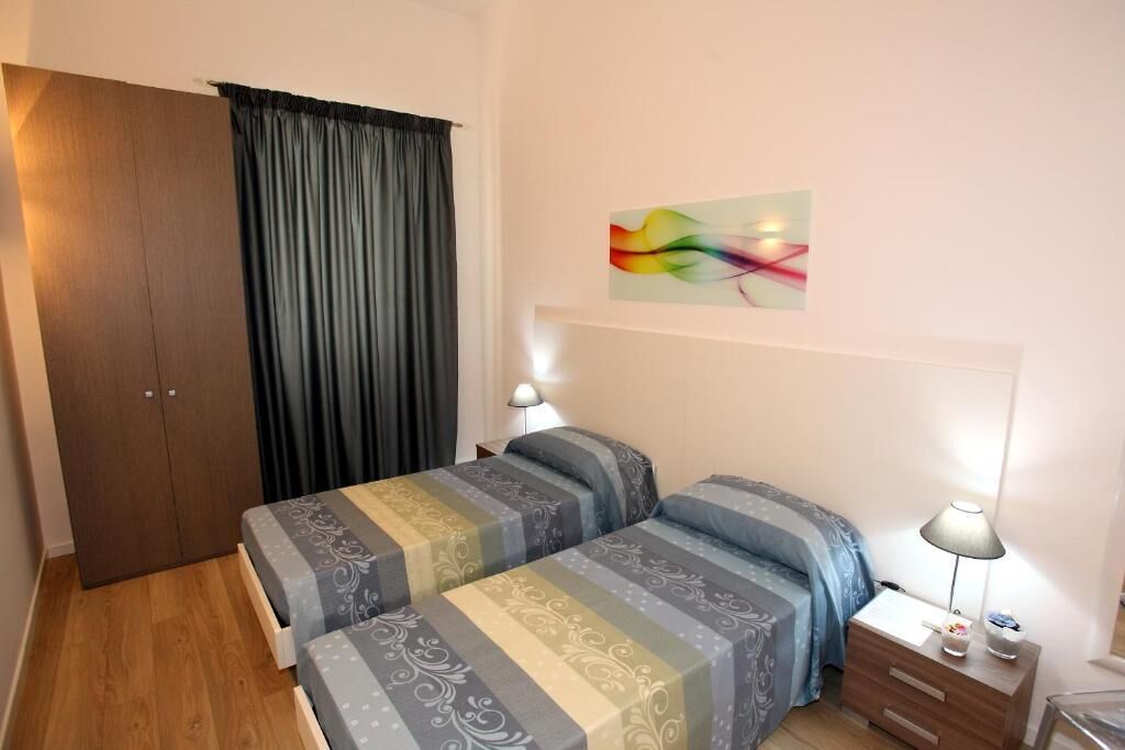 A bedroom with two beds, a wardrobe, a nightstand, and a wall art piece.