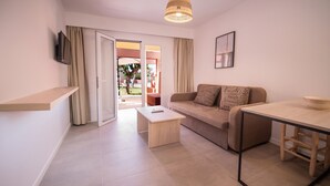 Una sala de estar moderna con sofá, una mesa de centro, un televisor montado en la pared y un comedor con mesa y sillas.